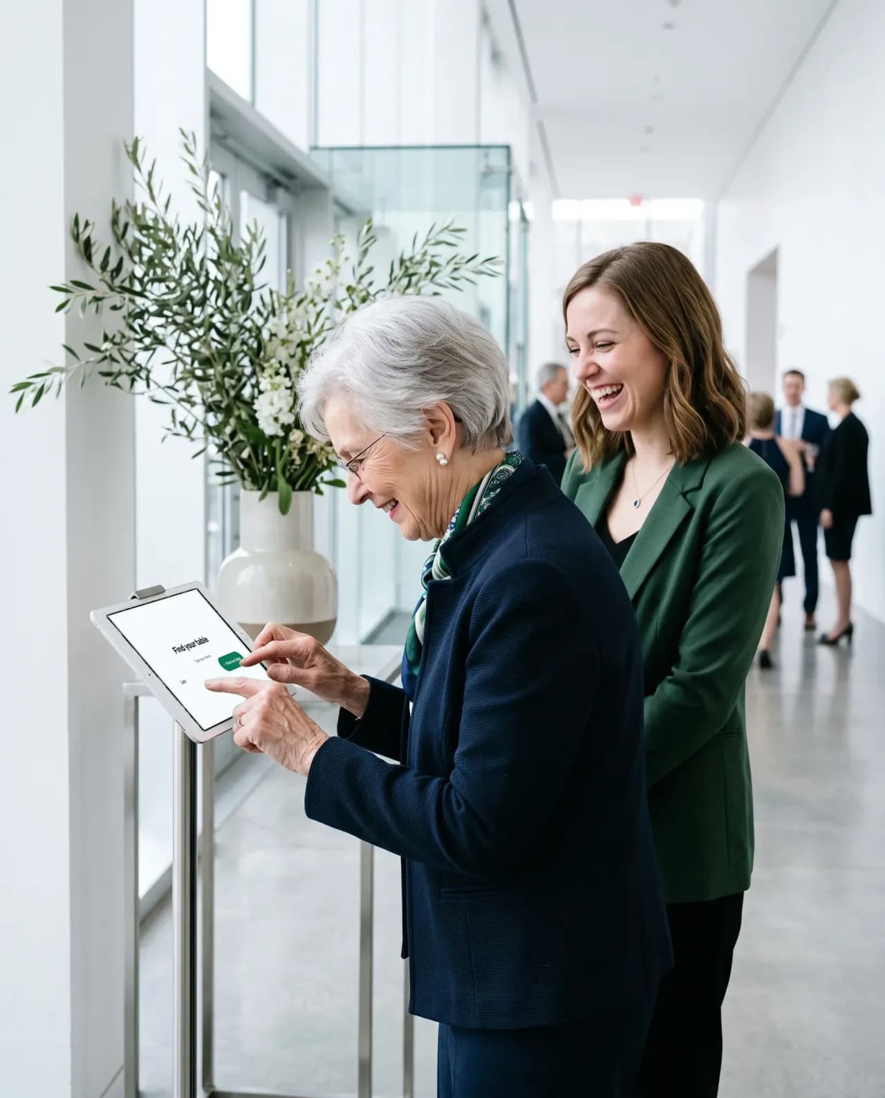 An older woman types her name on a tablet on a stand at a venue entrance while her granddaughter smiles beside her.
