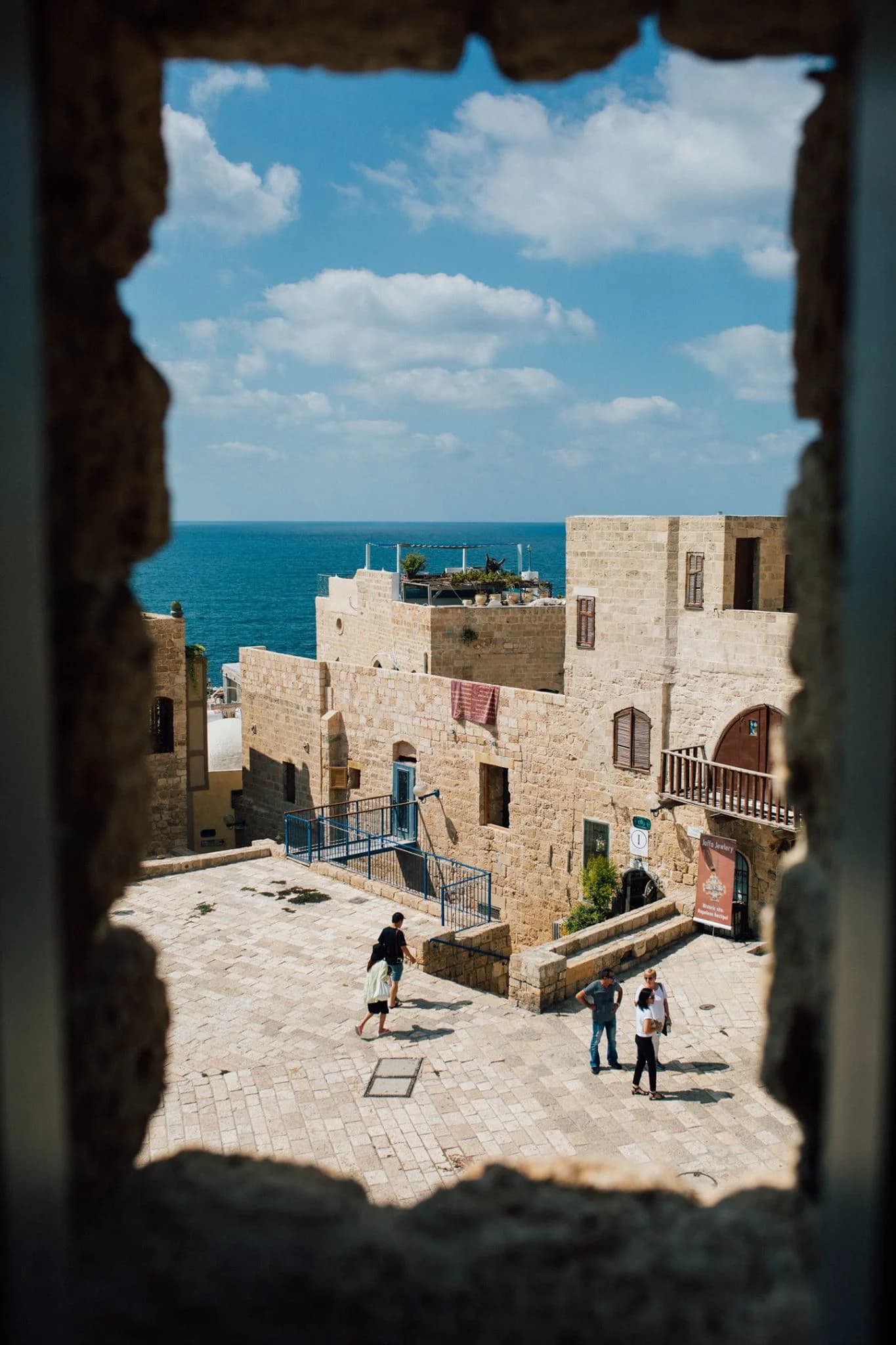 View of Old Jaffa stone buildings and the Mediterranean sea, framed through a weathered stone window