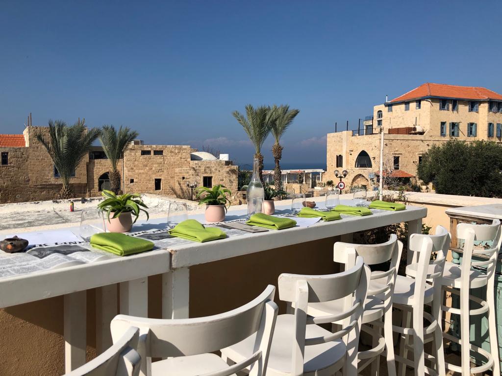 Long table on the rooftop terrace overlooking palm trees, Old Jaffa stone buildings and the sea