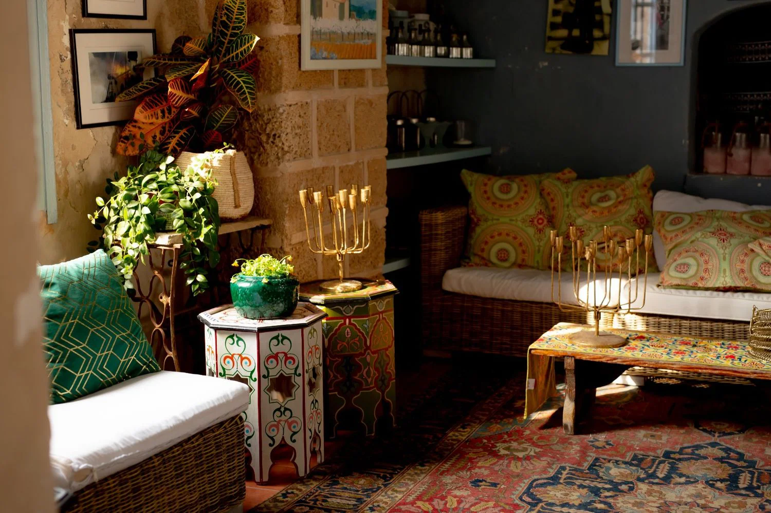 Cozy interior of Otzarin with art on the walls, gold candelabra, Moroccan rugs and warm cushions